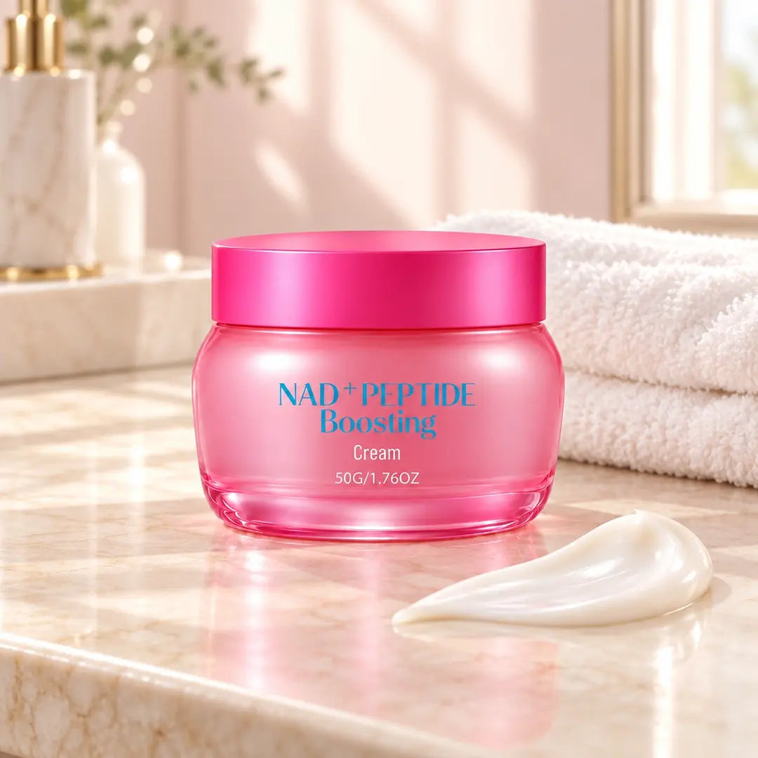 Pink 50 g jar of NAD+ Peptide Boosting Face Cream on an ivory vanity beside a white cream swatch and folded towels.
